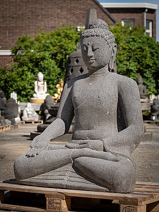 Buddha statue in lavastone, three-quarter left view showing the varada mudra hand