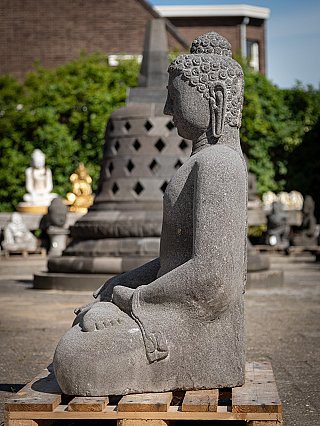Lavastone Buddha statue seated, left side profile on a wooden pallet