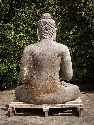 Indonesian lava stone Buddha statue, seated, rear view on a wooden pallet