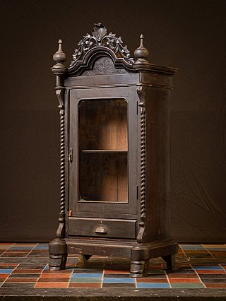 Antique wooden temple cabinet from Burma in three-quarter view with glass door and drawer