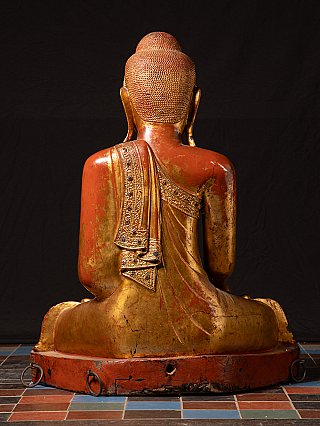 Rear view of the wooden Buddha statue showing red lacquered back and draped robe band