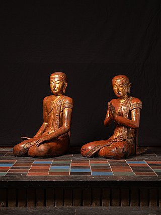 Pair of Burmese wooden monk statues, seated, right figure with folded hands, three-quarter view