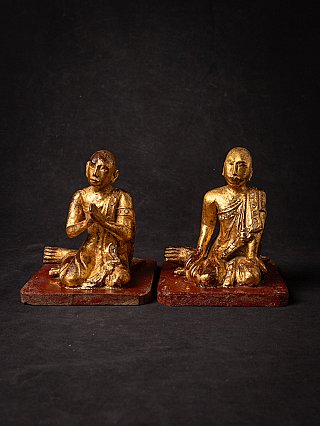 Burmese wooden monk statues seated with hands in prayer, frontal view