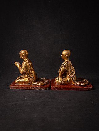 Burmese wooden monk statues seated on bases, side profile view