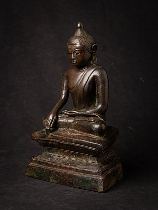 Bronze Burmese Buddha statue seated, three-quarter view showing the stepped pedestal