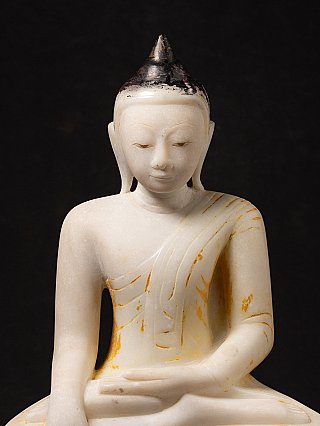 Gesichtsdetail der Marmor-Buddha-Statue mit geschlossenen Augen und dunkler Haarkappe