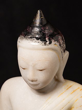 Nahaufnahme von Haarkappe und Gesicht der Marmor-Buddha-Statue mit Abrieb und Farbresten