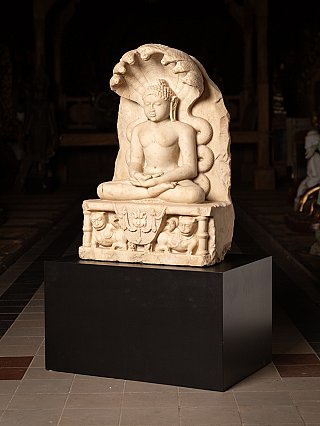 Marble Jain statue from India seated in meditation, three-quarter view with cobra hood and base relief