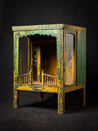 Antique wooden Indian temple shrine in three-quarter view, open front with worn green and yellow paint