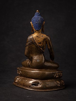 Rear view of the Tibetan bronze Buddha statue with blue hair and worn back surface