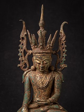 Close-up of the Burmese bronze Buddha statue face with tall crown and side ornaments