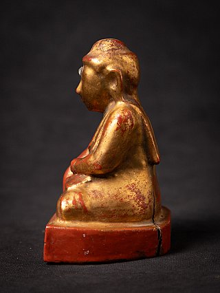 Burmese wooden Buddha statue with red and gold finish, left side profile