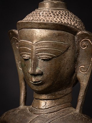 Angled face detail of the Burmese bronze Buddha showing incised eyebrows and nose