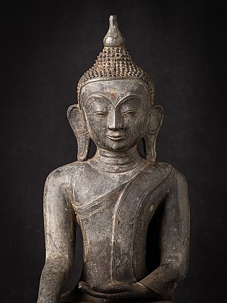 Front face detail of the Burmese bronze Buddha statue with curled hair and long earlobes