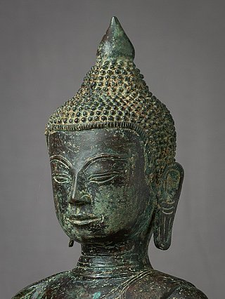 Zijwaarts detail van het bronzen Boeddhahoofd met patina en haarlokken