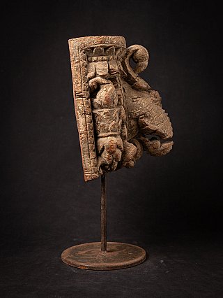 Houten tempelfragment uit India op standaard, schuin zijaanzicht met uitlopende krulvorm