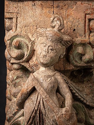 Head detail of the relief figure with headdress and traces of paint on the wood