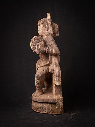 Indian wooden statue holding a round disc, left side profile view
