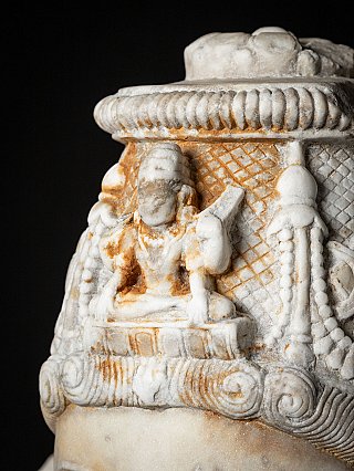 Crown detail with small carved figure on top of the marble bust