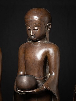 Close-up of the face and alms bowl on a bronze monk statue from Burma (Myanmar)