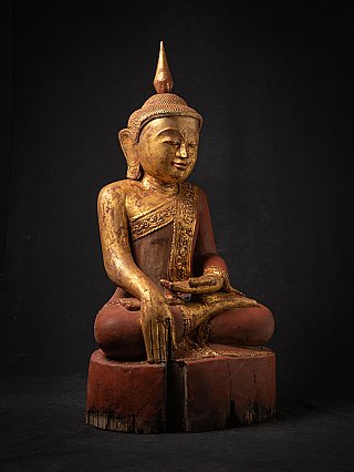 Burmese wooden Buddha statue in three-quarter view, bhumisparsha hand reaching down