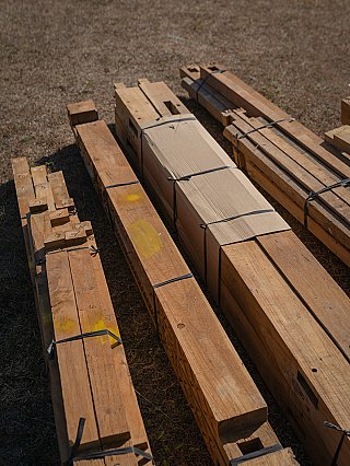 Bundled wooden beams and packaged parts for the temple house on the ground