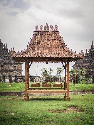 Indonesian teak temple house with tiled roof and open platform, front view outdoors