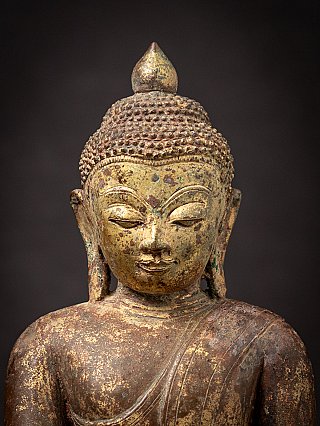 Straight-on face detail of the Burmese bronze Buddha with elongated earlobes