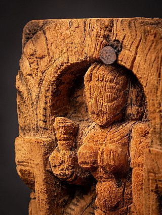 Close-up of Parvati’s head and raised hand on the wooden relief, angled view