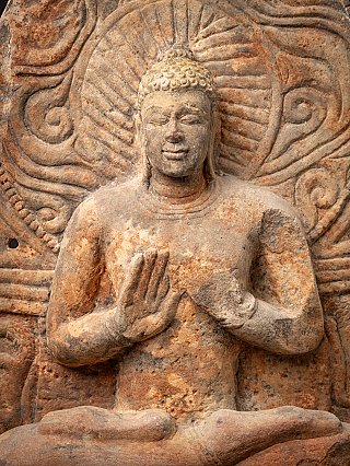 Close-up van de zittende Boeddha in reliëf, dharmachakra mudra voor de borst