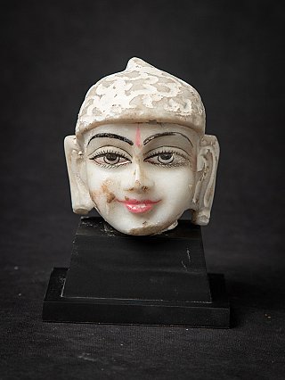 Marble head of a Jain statue from India on a black stand, full-front view