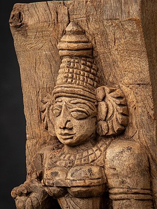 Angled detail of Devi’s headdress and ear ornaments on the wooden panel