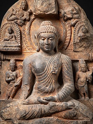 Upper body of the Buddha statue with halo and surrounding reliefs, frontal crop