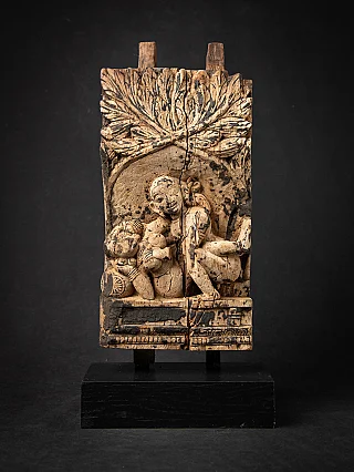 Antique wooden Indian temple panel showing relief figures beneath a large foliage canopy, front view