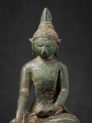 Close-up of head and chest on the Burmese bronze Buddha statue with green patina