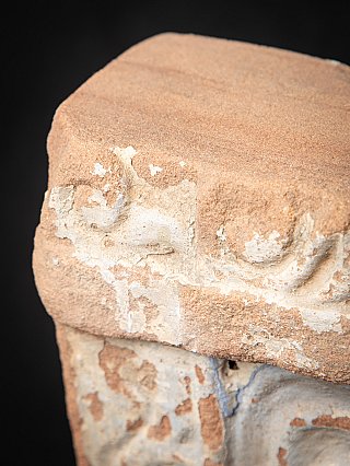 Top corner detail of the Indian stone shrine showing worn pale paint residues