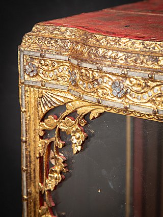 Detail of the gilded corner ornament with floral motif beneath the red top panel
