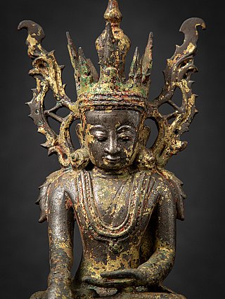 Front face detail of a Burmese bronze Buddha, with tall crown points and remnants of gilding