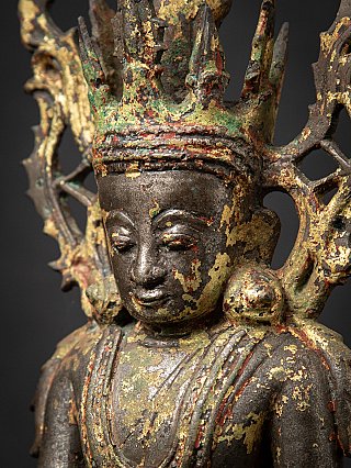 Angled head detail of the Burmese bronze Buddha, showing face, ear ornament and crown patina