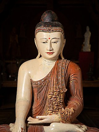 Gesichts- und Oberkörperdetail der Buddha-Statue mit roter Urna und verzierter Stirnborte