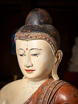 Kopfdetail des Buddha mit schwarzem Haarknoten und farbig eingelegter Stirnborte