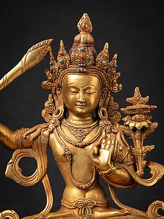 Face detail of the Manjushri statue with ornate crown and turquoise and coral-colored inlay