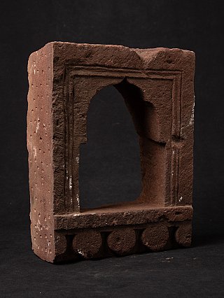 Indian stone temple niche in angled view with arched opening and rounded base elements