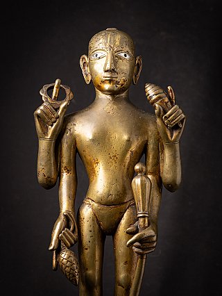 Front detail of the bronze Vishnu statue showing face, chest, and both raised hands