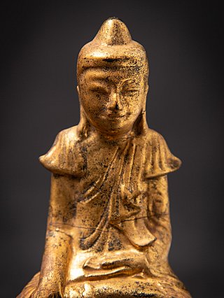 Frontal head and chest detail of the wooden Buddha statue, showing worn surface