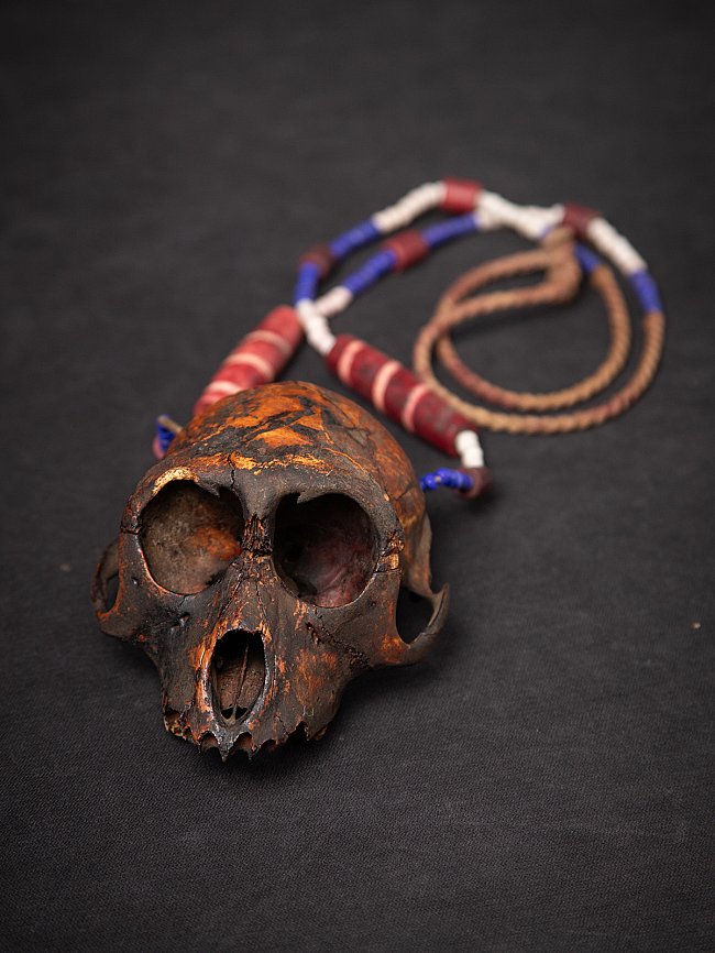 Naga necklace from Burma (Myanmar) with wooden monkey skull, angled front view on black background