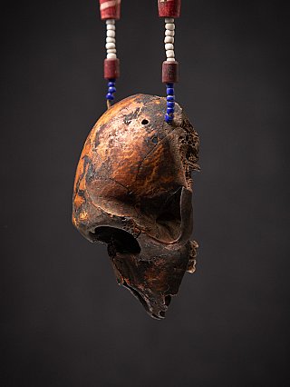 Side profile of the wooden monkey skull on the Naga necklace, showing the jaw area