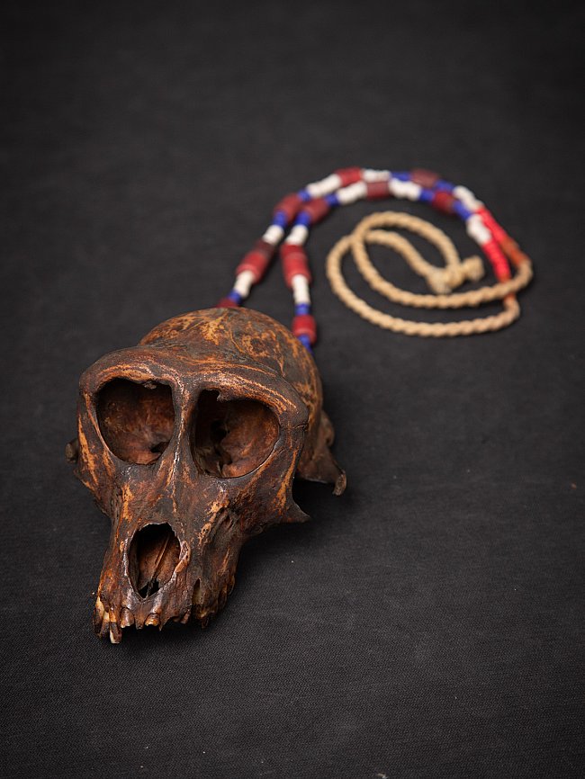 Old Naga necklace from Burma (Myanmar) with wooden monkey skull and bead strand, angled view