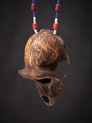 Wooden monkey skull on beaded necklace, side profile showing the skull dome