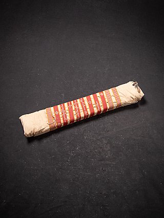 Rolled protective cloth wrap with woven band, shown on dark background
